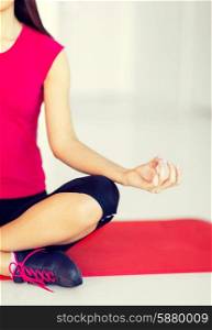 sport and yoga concept - girl sitting in lotus position and meditating