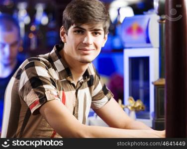 Sport bar. Young man in shirt sitting at bar
