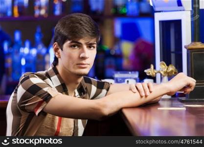 Sport bar. Young man in shirt sitting at bar