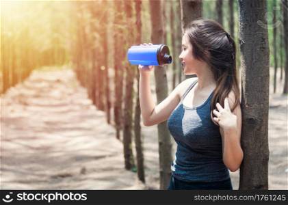 Sport beautiful young woman girl lifestyle exercise healthy drinking water after running workout in forest nature park with copy space