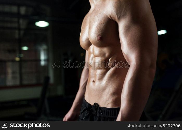sport, bodybuilding, fitness and people concept - close up of male body or bare torso in gym. close up of male body or bare torso in gym