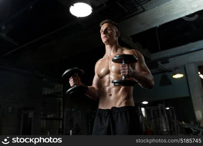 sport, bodybuilding, fitness and people concept - close up of young man with dumbbells flexing muscles in gym. close up of man with dumbbells exercising in gym