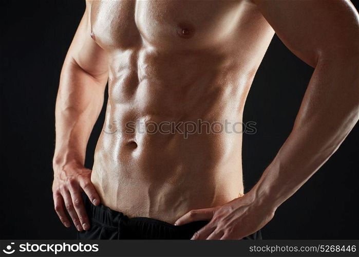 sport, bodybuilding, fitness and people concept - close up of young man or bodybuilder with bare torso over black background. close up of man or bodybuilder with bare torso