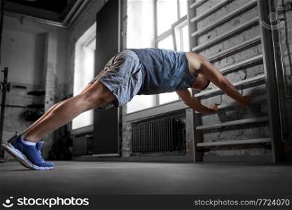 sport, bodybuilding, fitness and people concept - young man exercising on gymnastics wall bars in gym. man exercising on gymnastics wall bars in gym
