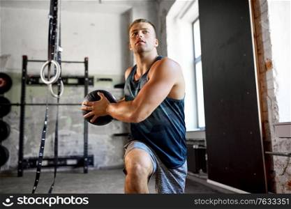 sport, bodybuilding, fitness and people concept - young man exercising with medicine ball in gym. young man exercising with medicine ball in gym