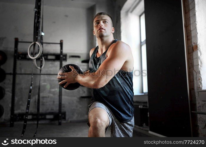 sport, bodybuilding, fitness and people concept - young man exercising with medicine ball in gym. young man exercising with medicine ball in gym