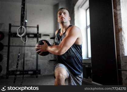 sport, bodybuilding, fitness and people concept - young man exercising with medicine ball in gym. young man exercising with medicine ball in gym