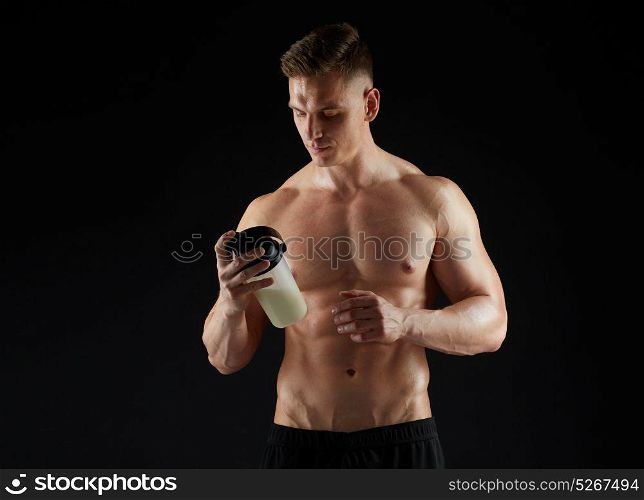 sport, bodybuilding, fitness and people concept - young man or bodybuilder with protein shake bottle and bare torso over black background. young man or bodybuilder with protein shake bottle