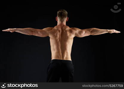 sport, bodybuilding, fitness and people concept - young man or bodybuilder with bare torso over black background from back. young man or bodybuilder with bare torso