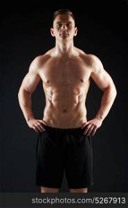 sport, bodybuilding, fitness and people concept - young man or bodybuilder with bare torso over black background. young man or bodybuilder with bare torso