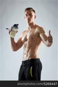 sport, bodybuilding, fitness and people concept - young man or bodybuilder with protein shake bottle and bare torso showing thumbs up. bodybuilder with protein shake showing thumbs up