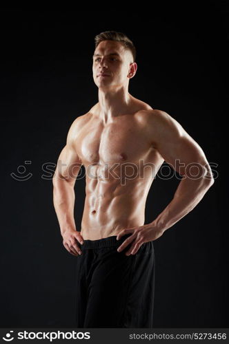 sport, bodybuilding, fitness and people concept - young man or bodybuilder with bare torso over black background. young man or bodybuilder with bare torso