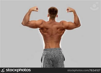 sport, bodybuilding, fitness and people concept - young man or bodybuilder with bare torso showing his muscles. young man or bodybuilder with bare torso