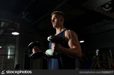 sport, bodybuilding, fitness and people concept - young man with dumbbells flexing muscles in gym. young man with dumbbells exercising in gym