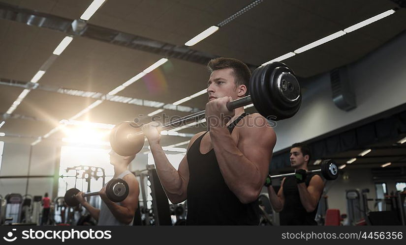 sport, bodybuilding, lifestyle and people concept - group of men with barbell flexing muscles in gym