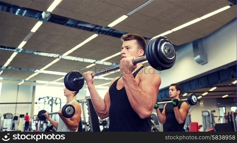 sport, bodybuilding, lifestyle and people concept - group of men with barbell flexing muscles in gym