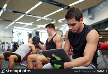 sport, bodybuilding, lifestyle, technology and people concept - group of men with tablet pc computer flexing muscles in gym