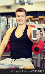 sport, bodybuilding, lifestyle, technology and people concept - smiling young man showing smartphone blank screen in gym