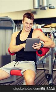 sport, bodybuilding, lifestyle, technology and people concept - smiling young man with tablet pc computer in gym