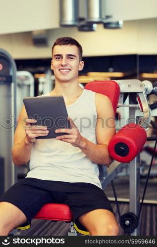 sport, bodybuilding, lifestyle, technology and people concept - smiling young man with tablet pc computer in gym