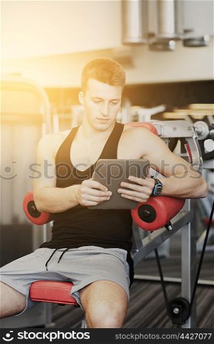 sport, bodybuilding, lifestyle, technology and people concept - young man with tablet pc computer in gym
