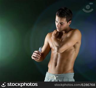 sport, bodybuilding, medicine and people concept - young man applying pain relief gel on his shoulder over dark background