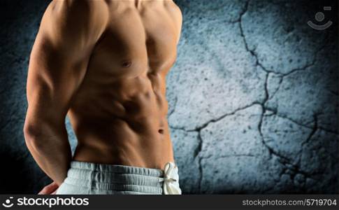 sport, bodybuilding, strength and people concept - close up of male bodybuilder bare torso over concrete wall background