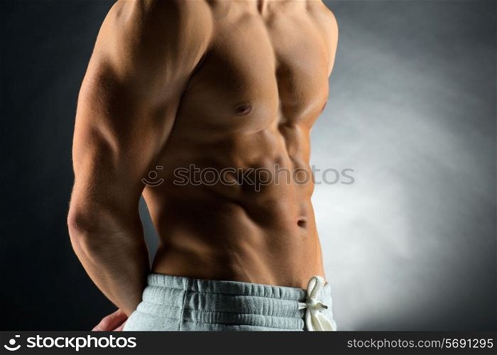 sport, bodybuilding, strength and people concept - close up of young man standing over black background