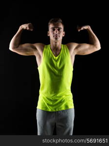 sport, bodybuilding, strength and people concept - young man showing biceps over black background