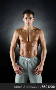 sport, bodybuilding, strength and people concept - young man standing over black background