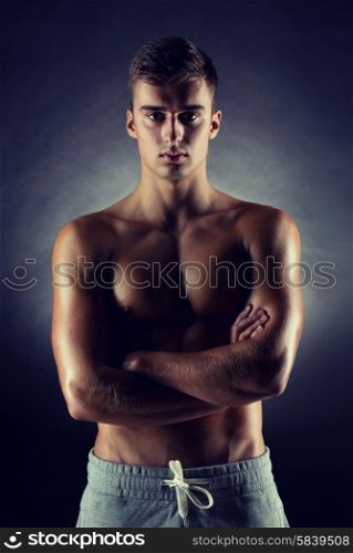 sport, bodybuilding, strength and people concept - young man standing over black background