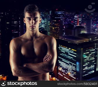 sport, bodybuilding, strength and people concept - young man with bare muscular torso standing over night city background