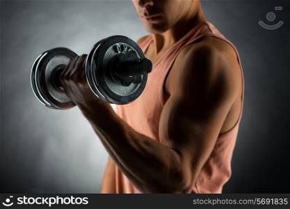 sport, bodybuilding, training and people concept - close up of young man with dumbbell flexing muscles over gray background
