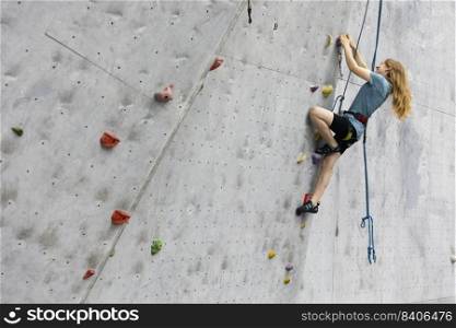 sport. bouldering, teen girl climbing up the wall 