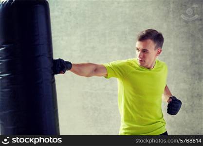 sport, box and people concept - young man in gloves boxing with punching bag in gym