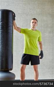 sport, box and people concept - young man with boxing gloves and punching bag in gym