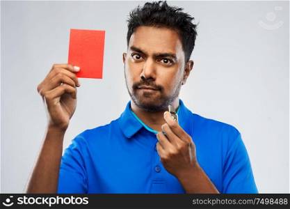 sport, caution, game and football concept - indian male referee with whistle and showing red penalty card. indian referee with whistle showing red card