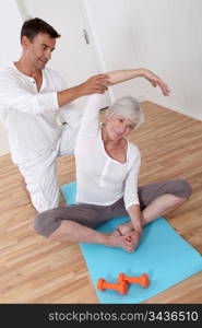 Sport coach training senior woman with stretching exercises