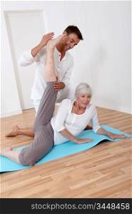 Sport coach training senior woman with stretching exercises