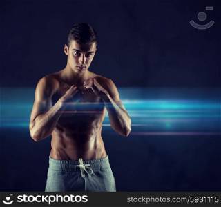 sport, competition, strength and people concept - young man in fighting or boxing position over dark background