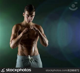sport, competition, strength and people concept - young man in fighting or boxing position over dark background