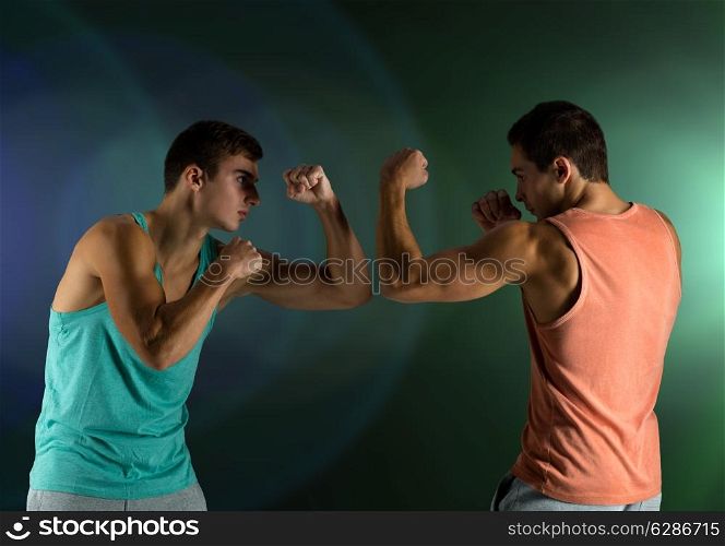 sport, competition, strength and people concept - young men fighting hand-to-hand over dark background