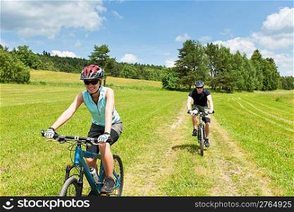 Sport couple riding mountain bicycles in coutryside meadows