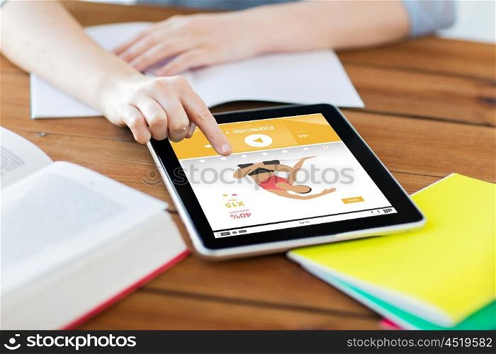 sport, education, technology and internet concept - close up of student woman with fitness application on tablet pc computer and notebook at home