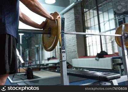 sport equipment, bodybuilding and people concept - close up of man or bodybuilder with barbell weight in gym. close up of man with barbell weight in gym