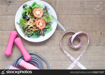Sport equipments, fresh salad and measuring-tape in heart shape, Healthy lifestyle concept