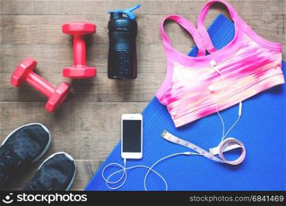 Sport equipments. Sport bra. Smartphone and sport shoes on wood floor