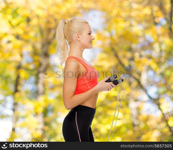 sport, exercise and healthcare concept - smiling sporty woman with skipping rope