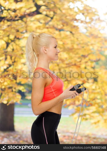 sport, exercise and healthcare concept - smiling sporty woman with skipping rope