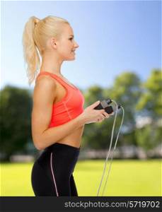 sport, exercise and healthcare concept - smiling sporty woman with skipping rope